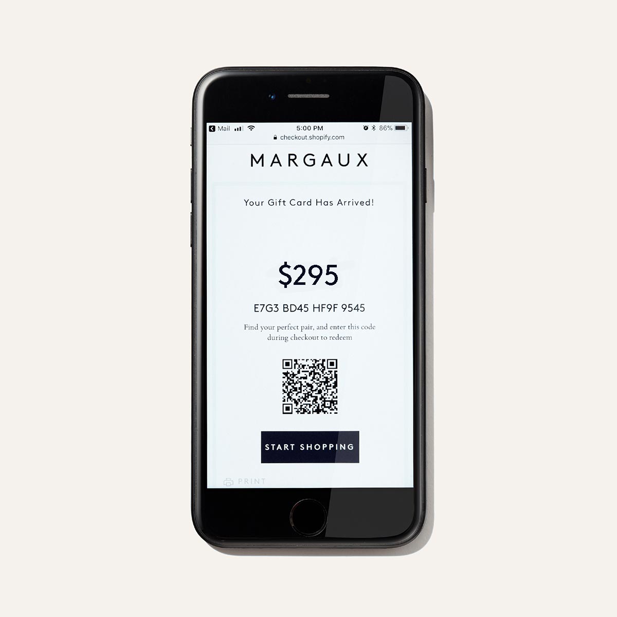 A smartphone displays The Bridal Atelier E-Gift Card by Margaux, valued at $295, with a redeemable code, QR code, and Start Shopping button on a white background—an ideal gift for luxurious bridal shoes.