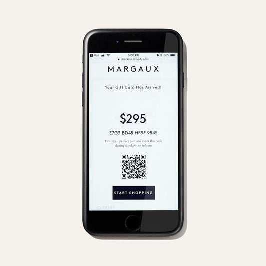 A smartphone displays The Bridal Atelier E-Gift Card by Margaux, valued at $295, with a redeemable code, QR code, and Start Shopping button on a white background—an ideal gift for luxurious bridal shoes.