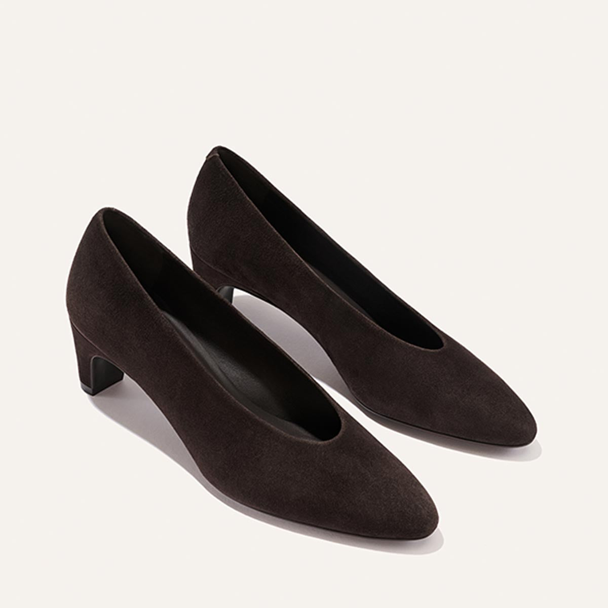 A pair of The Augusta Glove Pump in Molasses Suede by Margaux, featuring low heels and pointed toes, is displayed on a light background.
