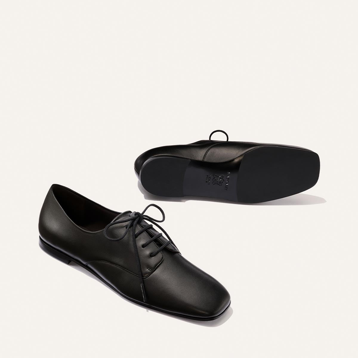 A pair of Margaux "The Billie Derby - Black Nappa" shoes, one shown from the side and the other from the bottom, are displayed on a plain white background.