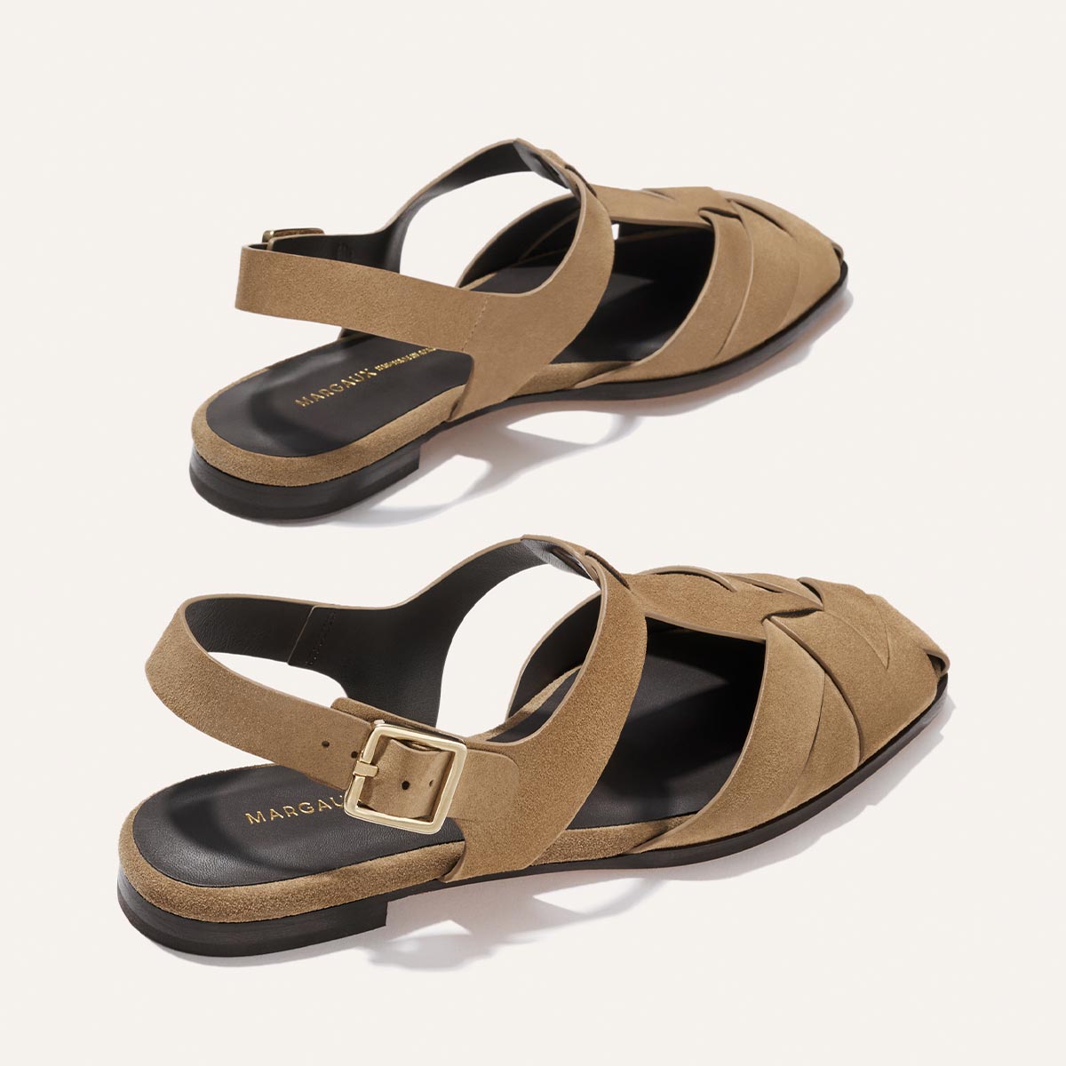 Pair of tan sandals with a buckle on a white background