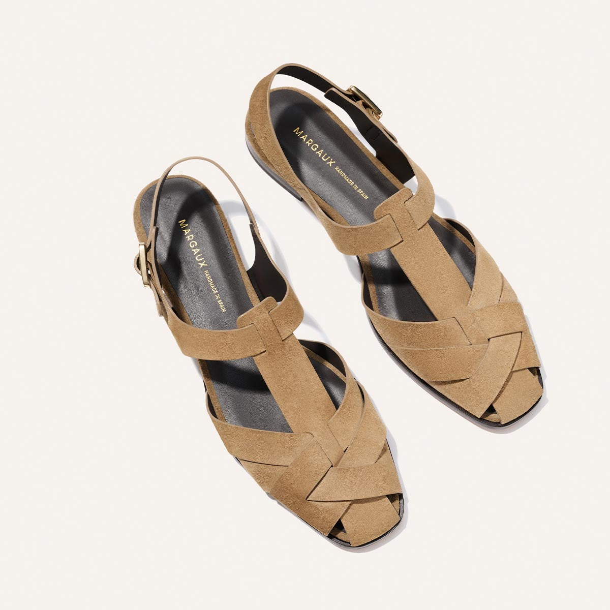 Pair of tan sandals with woven design on a white background