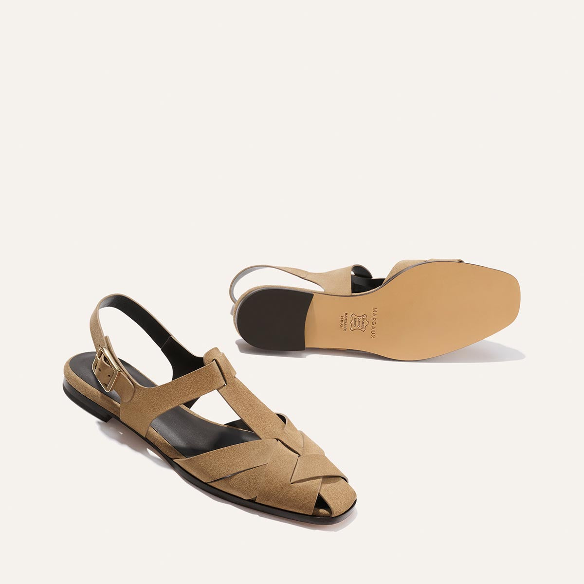 Tan sandals with a black sole on a white background