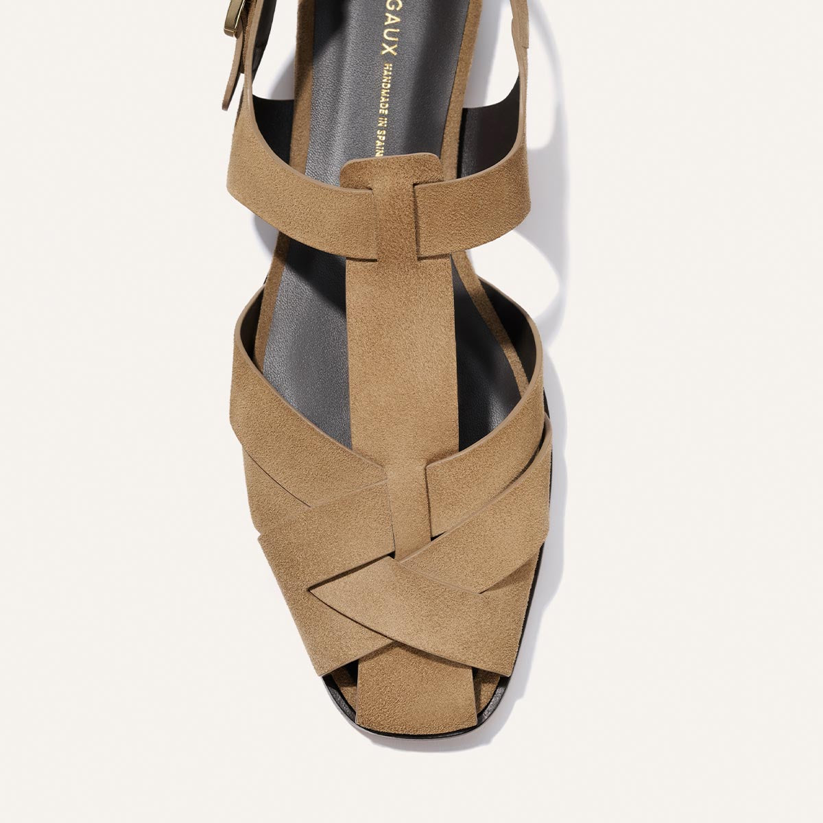 Tan sandal with criss-cross straps on a white background