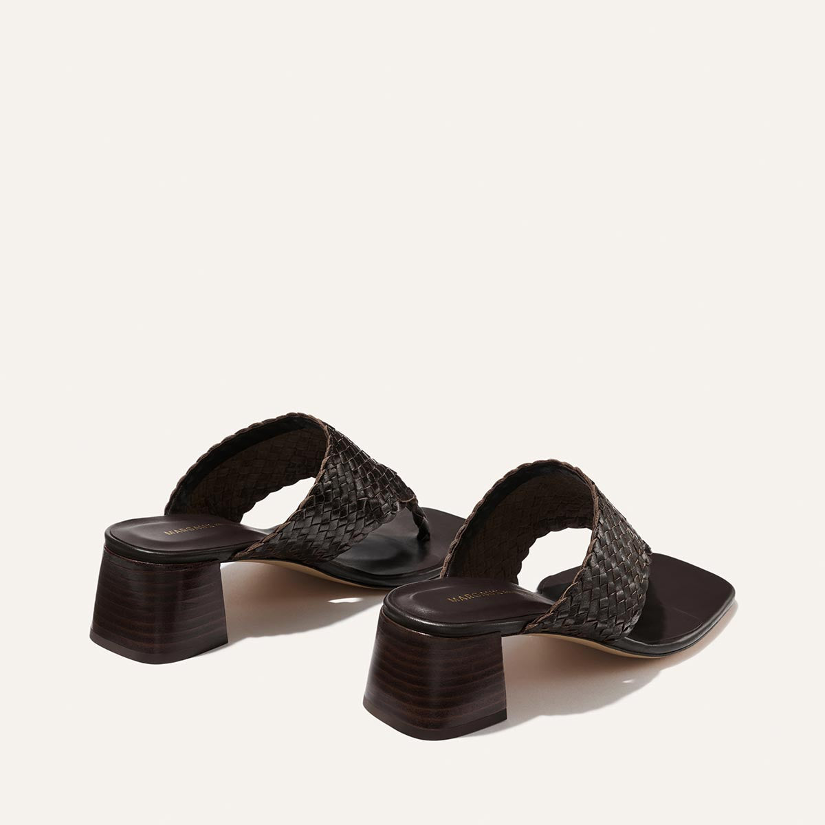 Pair of brown woven sandals on a light beige background