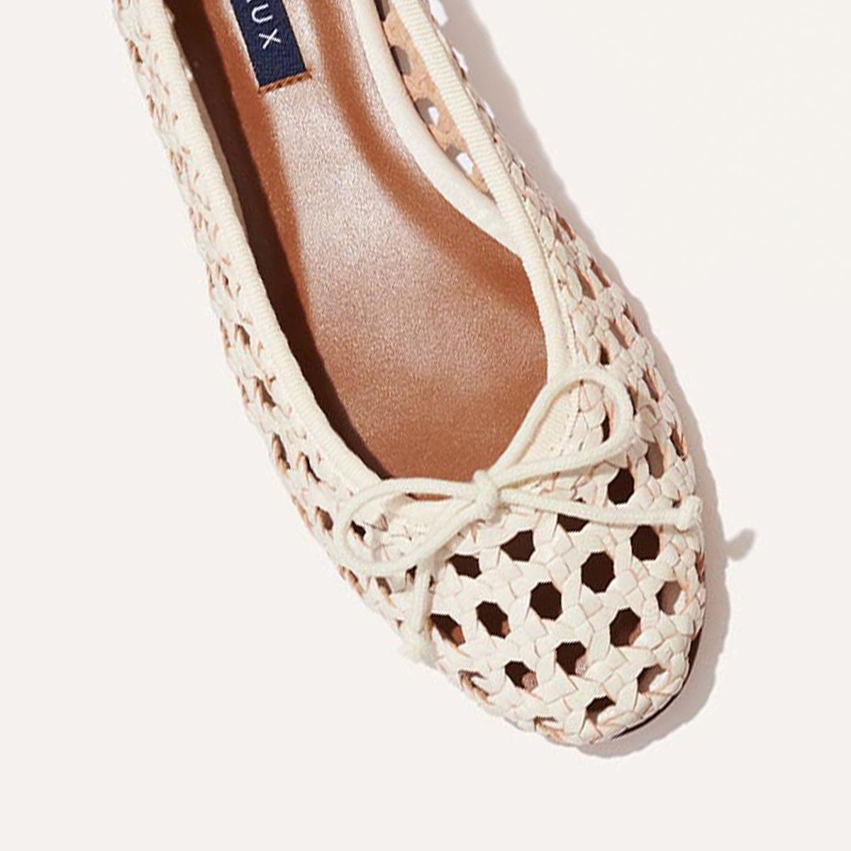 A close-up of The Demi - Ecru Woven Leather ballet flat by margaux-development, handmade in Spain with cream woven leather and a toe bow, shown against a light background.