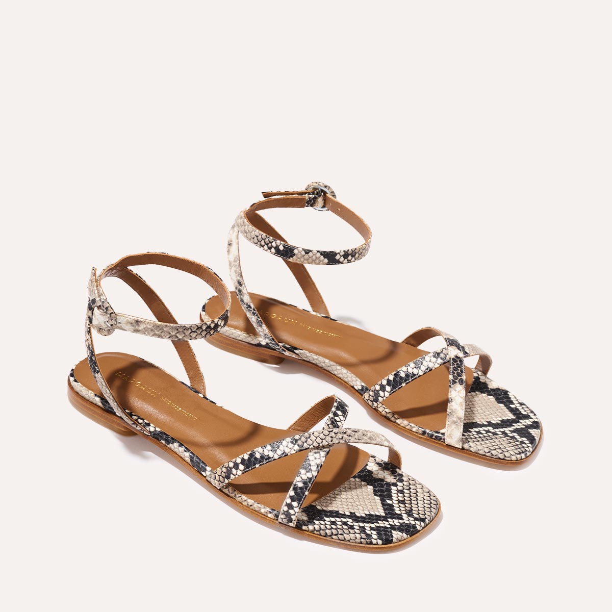 Step out in Margaux’s The Flat Sandal – Natural Python Embossed, featuring snakeskin-patterned straps, brown soles, ankle buckle straps, and a foam-cushioned insole for timeless style and all-day comfort.