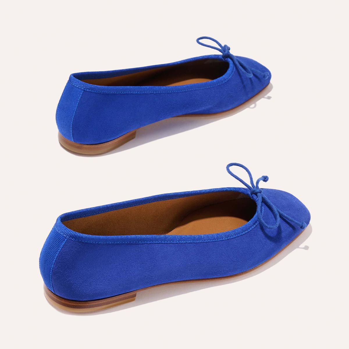 The Fonteyn - Cobalt Suede by Margaux features bright blue ballet flats with brown soles, rounded toes, and front bows, shown from two angles on a light background—combining comfort and stylish design for all-day wear.