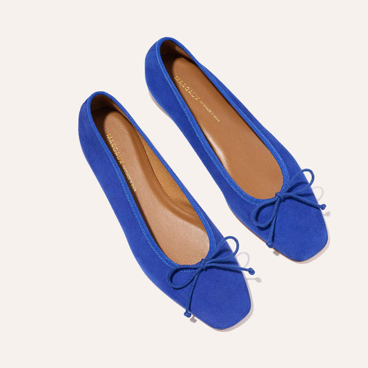 The Fonteyn - Cobalt Suede by Margaux features handcrafted bright blue suede ballet flats with square toes, tan insoles, and elegant front bows, shown against a light background.