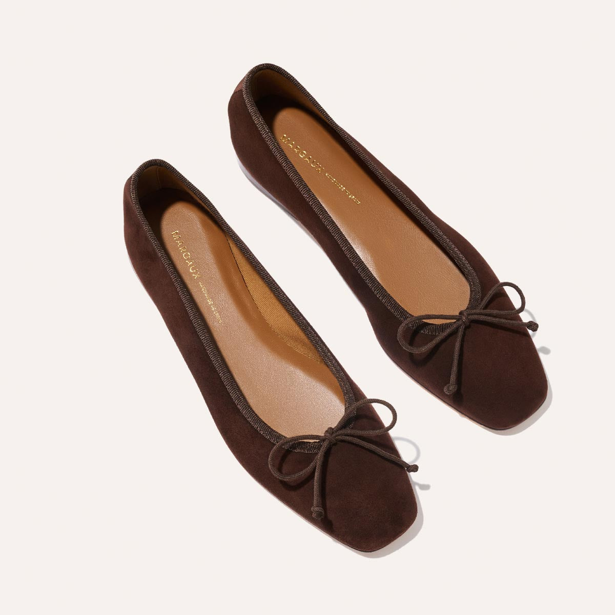 The Fonteyn - Espresso Suede by Margaux: handcrafted dark brown suede ballet flats with square toes and bow accents, displayed on a light background.