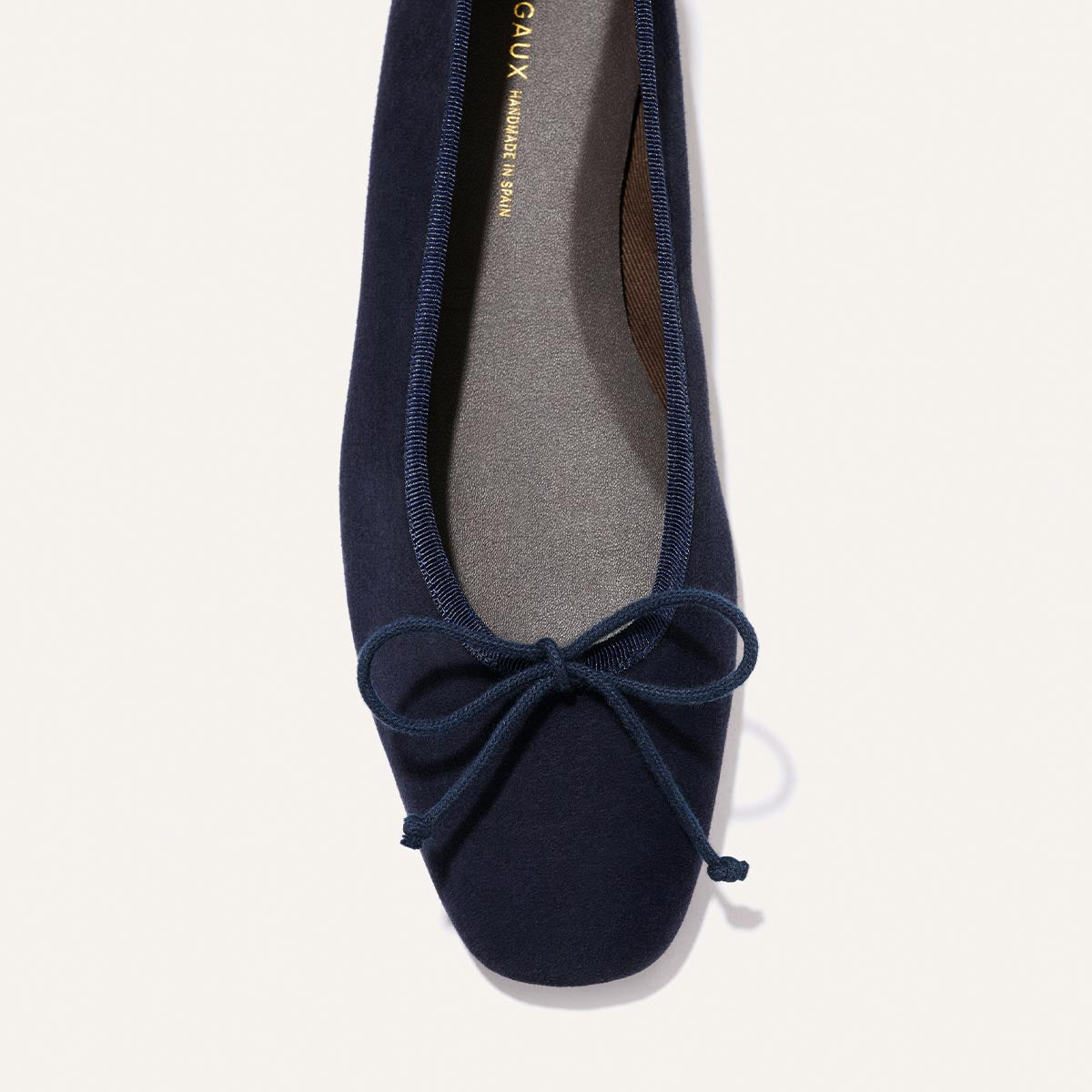 A close-up top view of Margaux's The Fonteyn - Indigo Suede ballet flat, featuring a small bow on the toe and a soft gray insole.