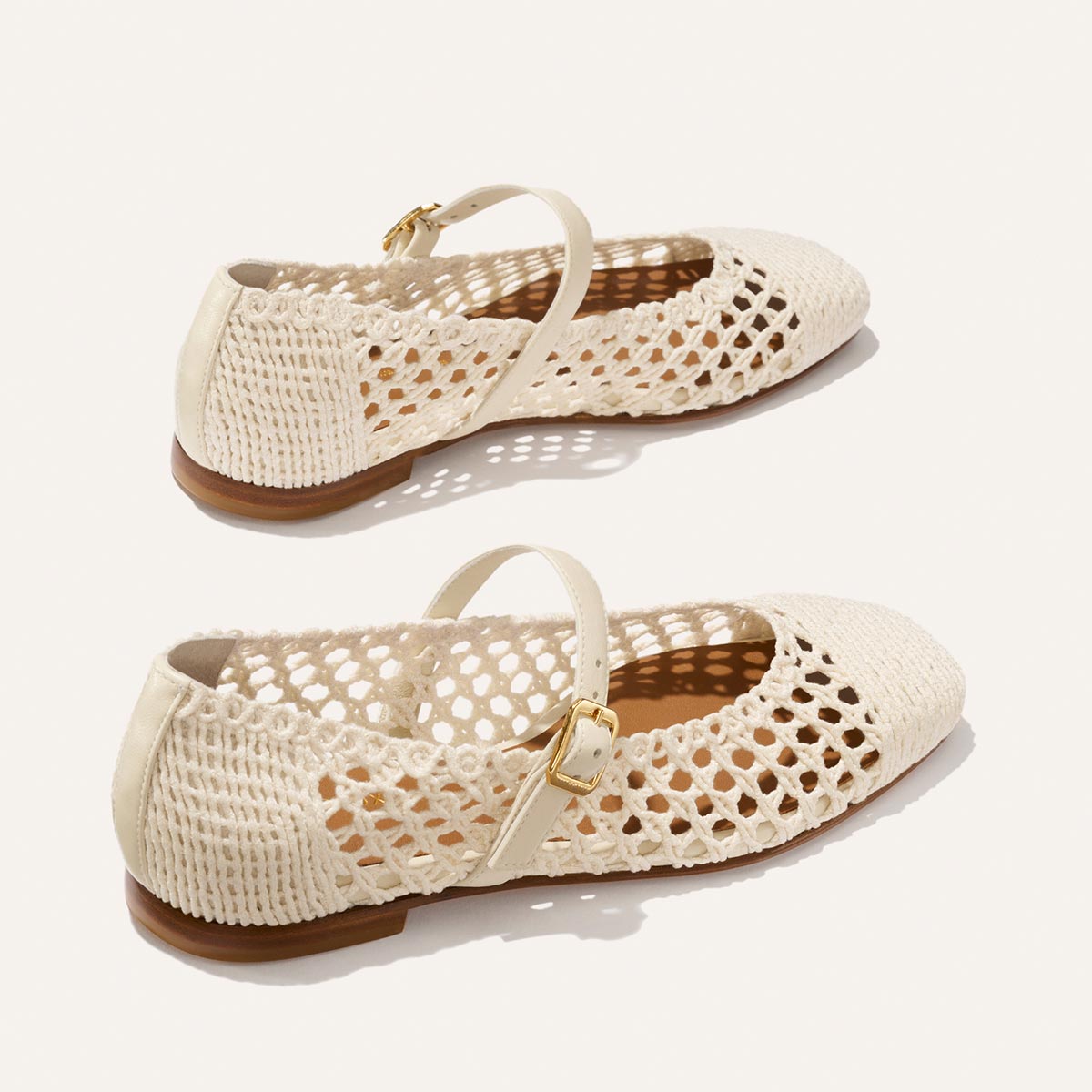 Margaux's The Fonteyn Jane - Ecru Macrame features cream-colored, woven Mary Jane flats with a mesh cotton design, adjustable gold-buckle strap, and tan soles, shown on a light background.