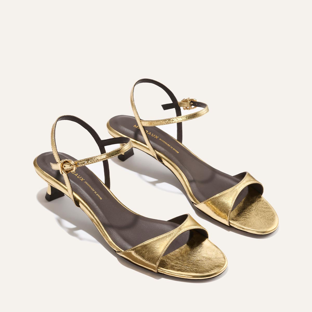 Gold high-heeled sandals on a white background