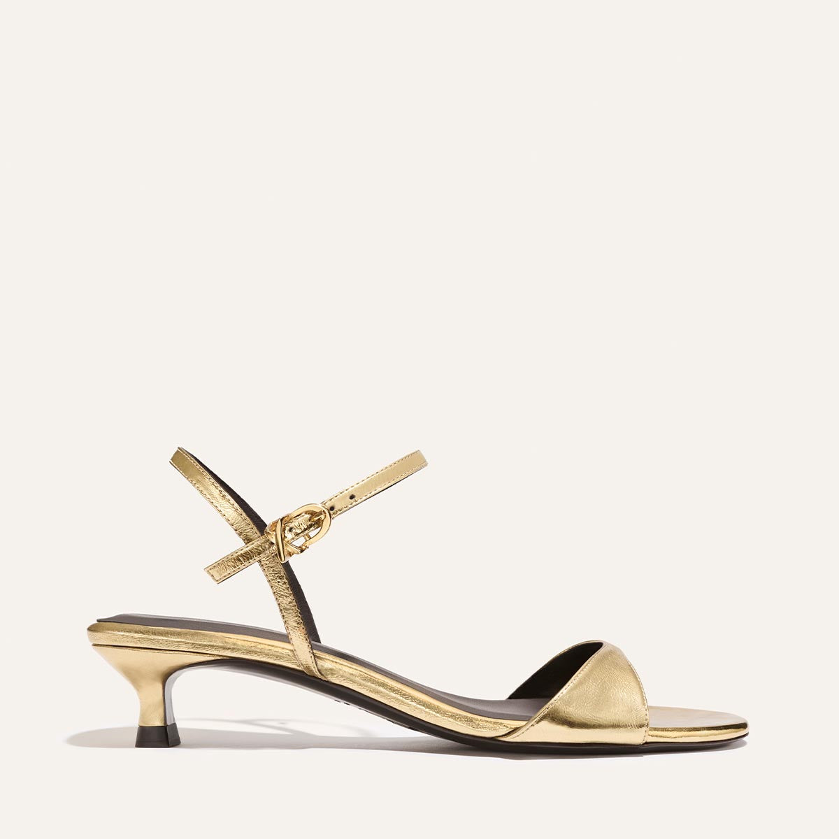 Gold sandal with a thin strap on a white background