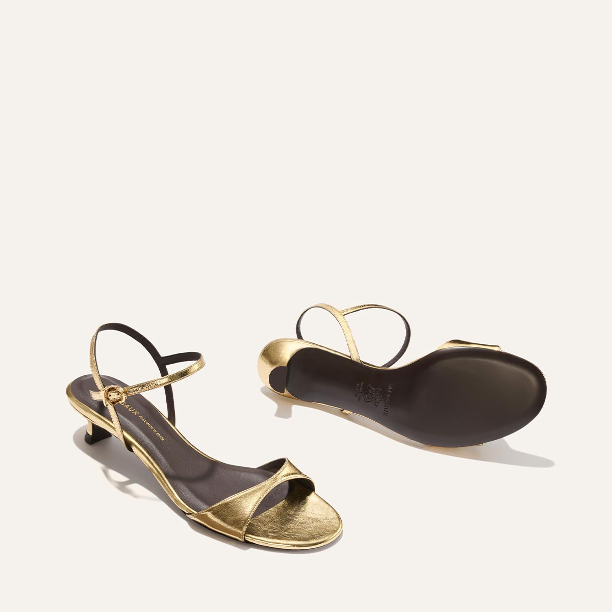 Pair of gold high-heeled sandals on a white background