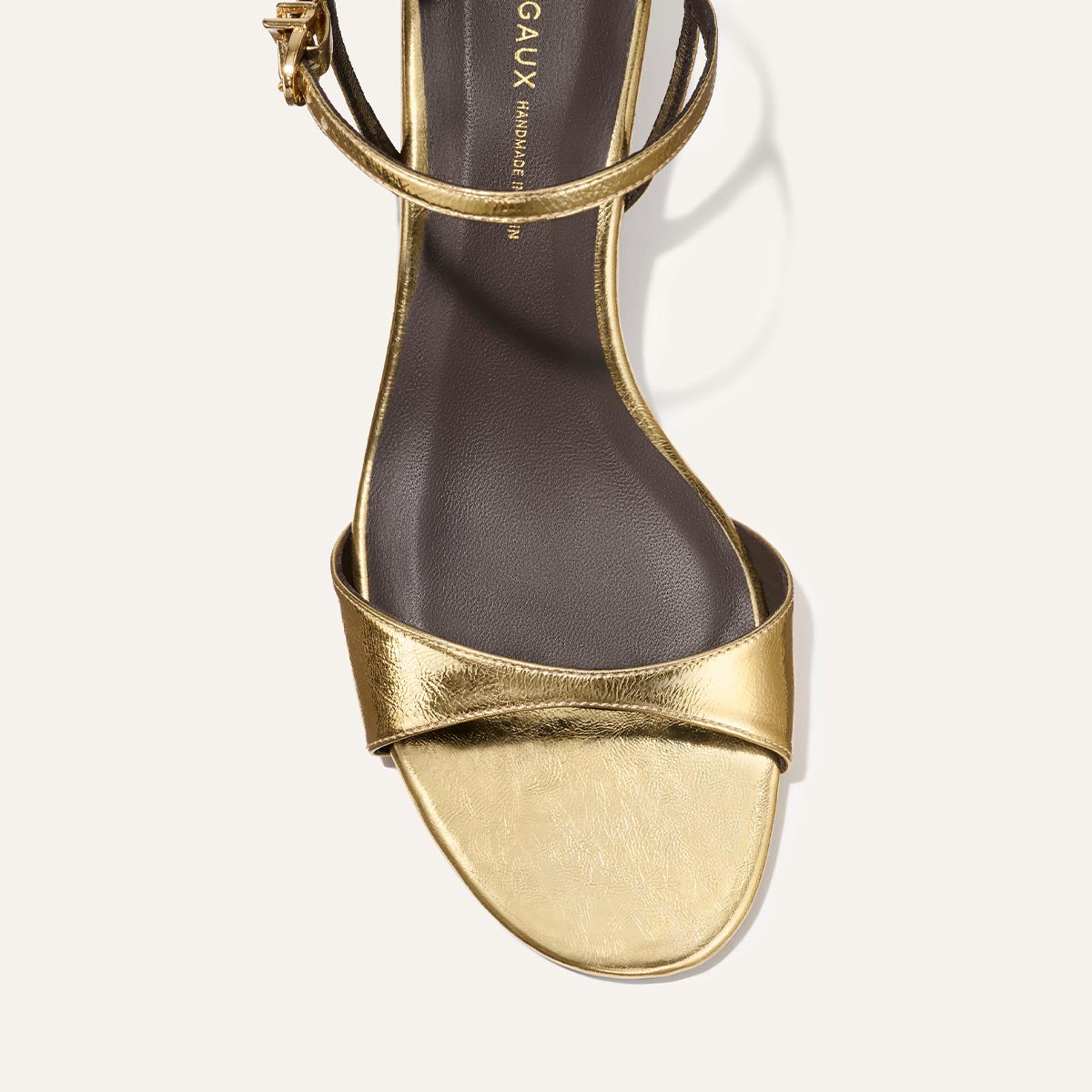 Gold sandal with thin strap on a white background