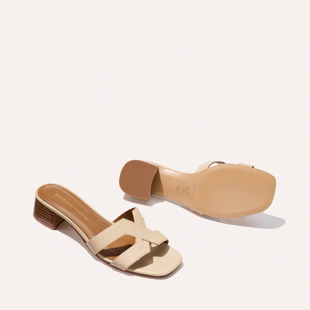 A pair of Margaux’s The MX 35 - Latte Calf open-toe sandals with crisscross straps and low block heels, displayed from the top and bottom on a light background.