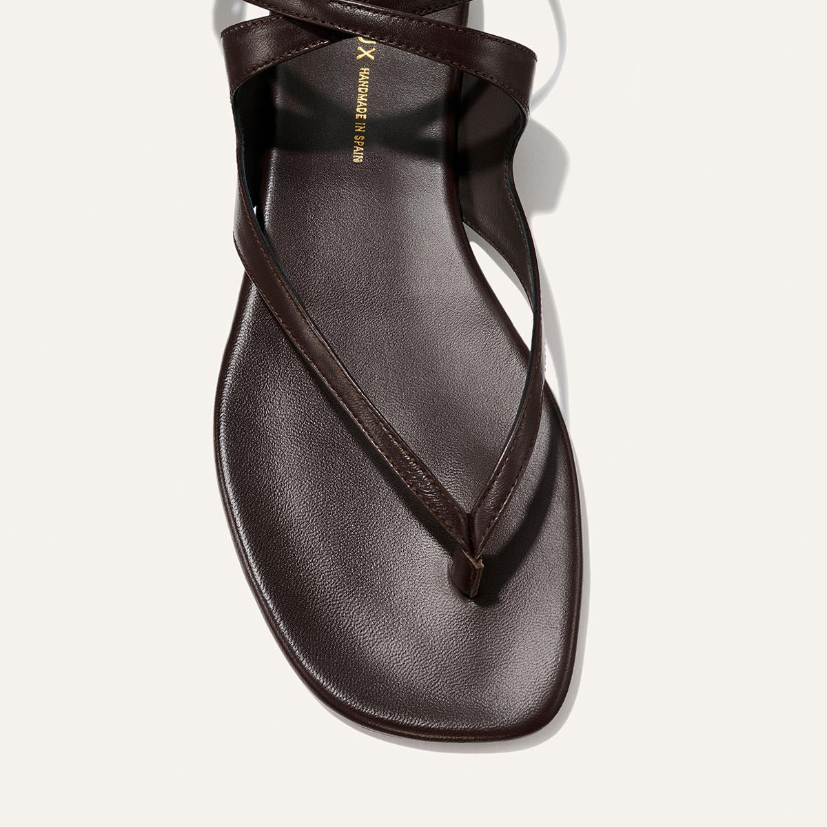 Brown sandal with a thin strap on a light gray background