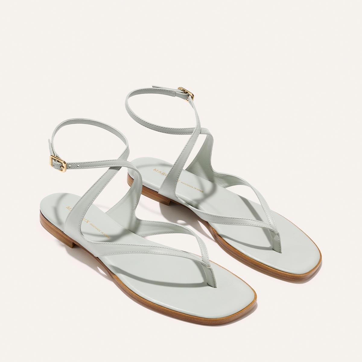 Pair of light blue sandals with thin straps on a white background