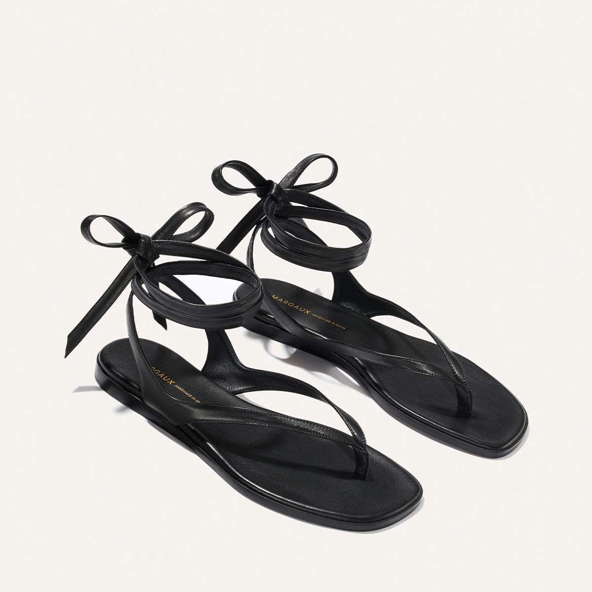 Black sandals with ribbon straps on a light gray background