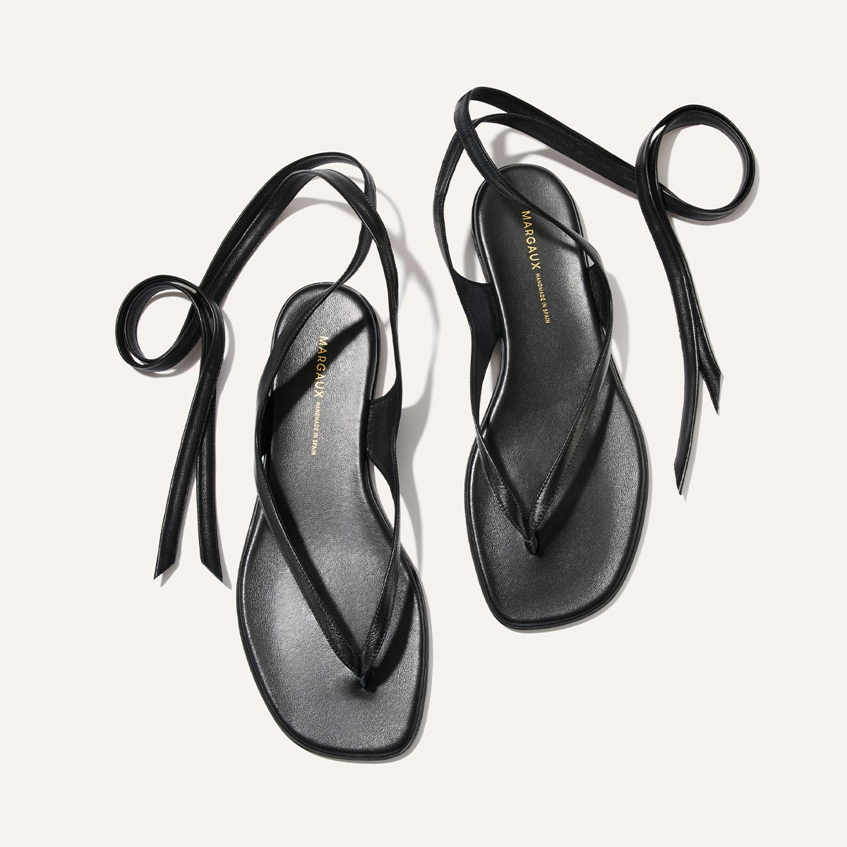 Black sandals with unique strap design on a light gray background