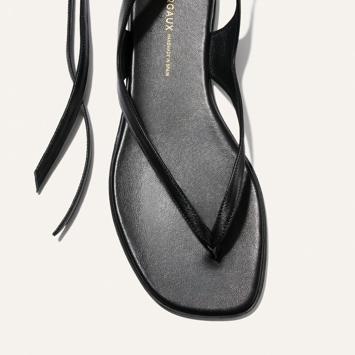 Black sandal with a minimalist design on a light gray background