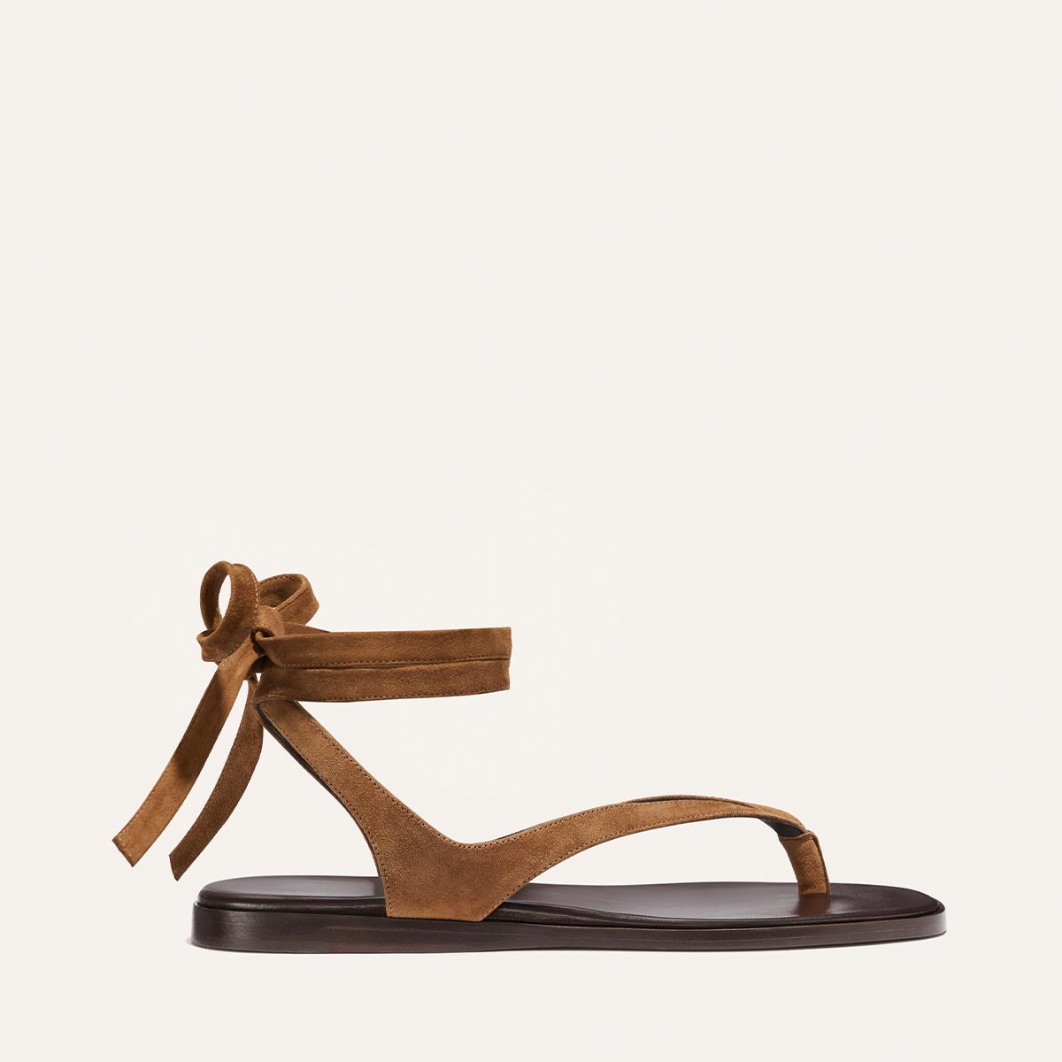 The Palermo Wrap Sandal in Nutmeg Suede by Margaux features a cushioned insole, toe loop, single strap, and an ankle bow tie—shown on a plain white background for effortless getaway style.