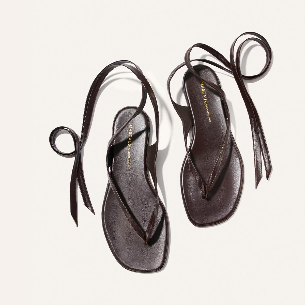 The Margaux Palermo Wrap Sandal in Espresso Nappa features dark brown leather, slim ankle wrap straps, square soles, and cushioned insoles—an ideal summer getaway style, beautifully displayed on a light background.
