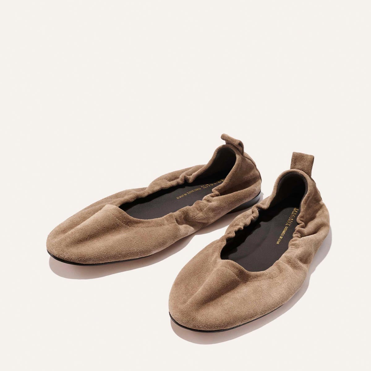 The Pascale - Cappuccino Suede by Margaux: light brown suede ballet flats with an elasticated ruched back and heel pull tabs, shown on a plain white background.