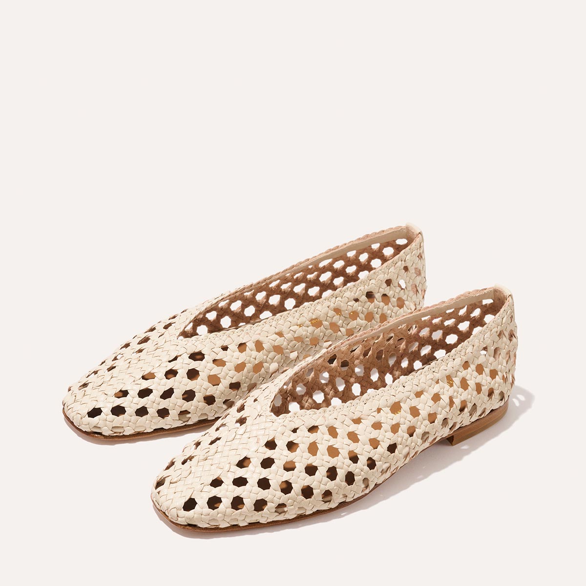 The Margaux Woven Paz SS25 - Ecru Leather features pointed toes and an open, airy cutout handwoven design, shown on a light background.