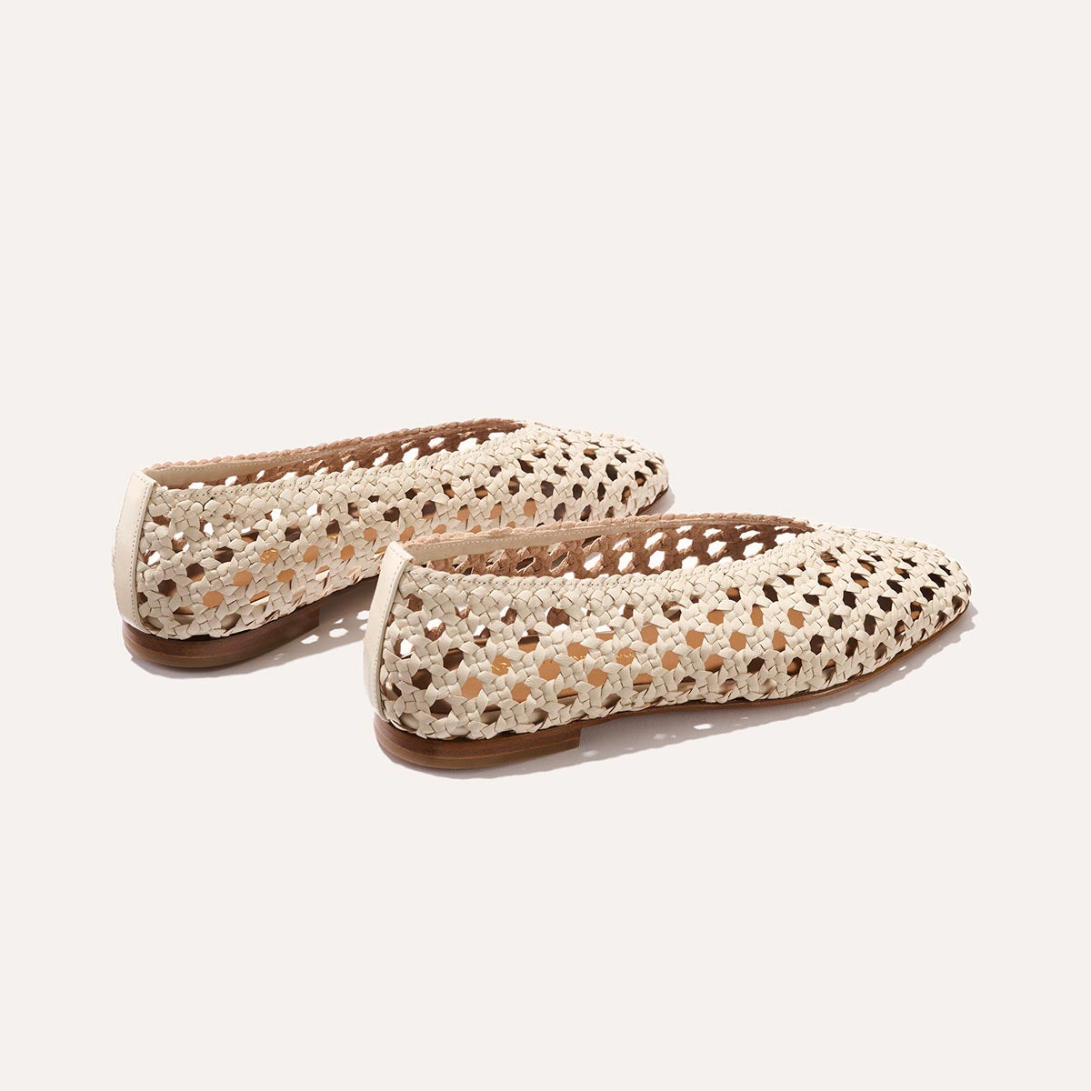 A pair of The Woven Paz SS25 - Ecru Leather flats by Margaux, featuring a handwoven crochet-inspired design and tan soles, displayed on a light background to showcase the sides and back.