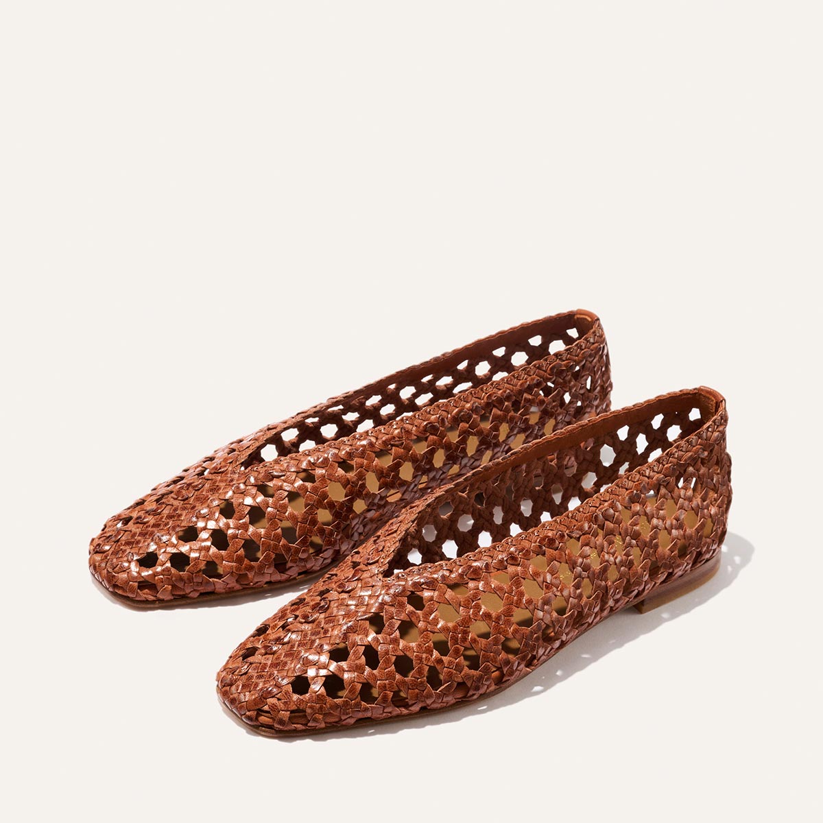 The Woven Paz - Saddle Woven Leather flats by Margaux feature a luxuriously soft, handwoven honeycomb pattern in brown leather, showcased on a simple light background.