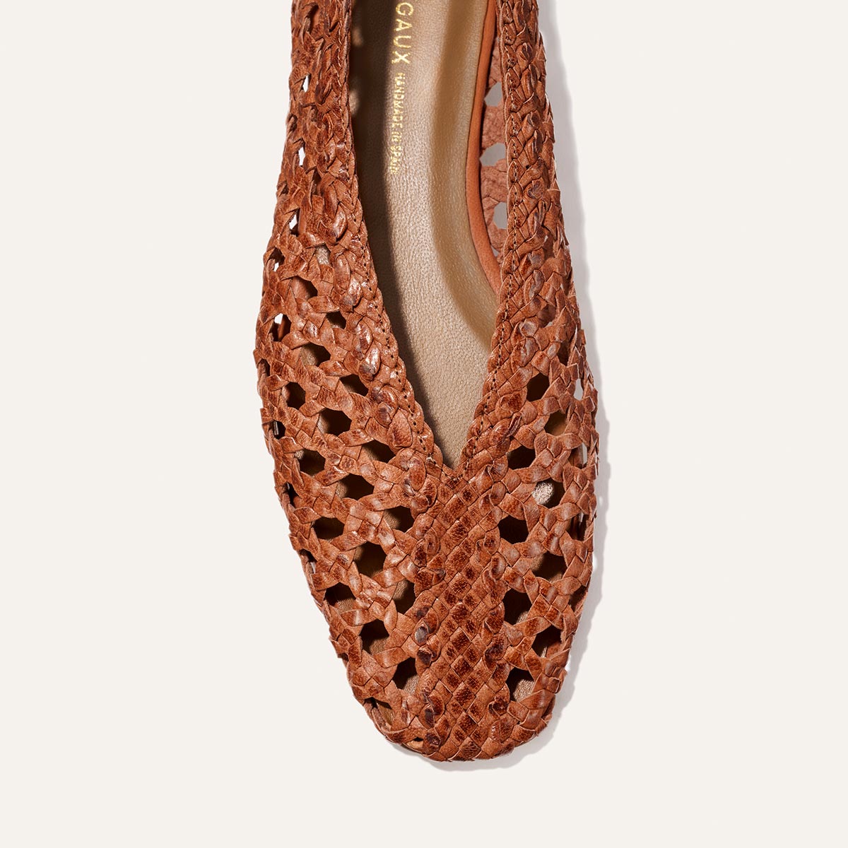 A close-up of Margaux’s The Woven Paz in Saddle Woven Leather, a brown flat shoe featuring a pointed toe and intricate star-shaped cut-outs on its soft, woven upper.