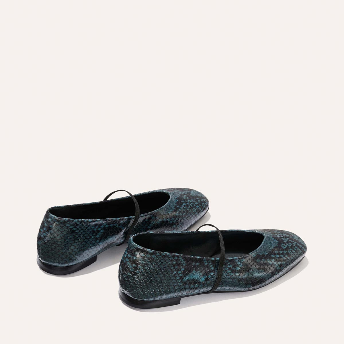 The Phoebe - Aqua Python Embossed by Margaux are flat, round-toe ballet shoes with a blue and black snakeskin pattern and thin black straps, shown on a light, neutral background.