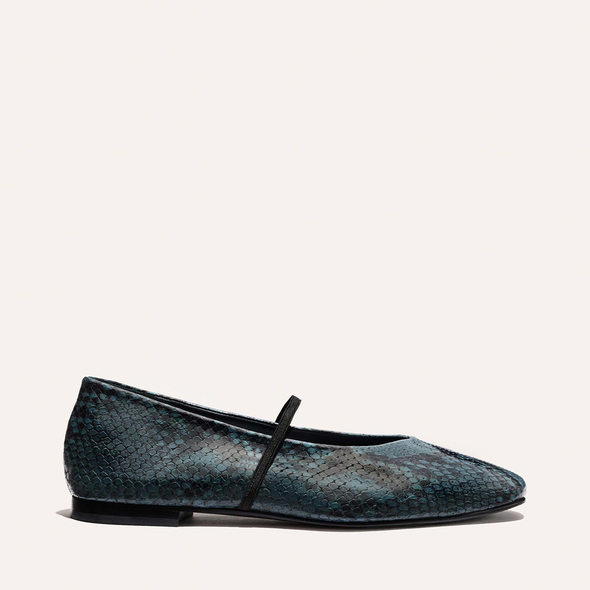 Margaux’s The Phoebe—a single flat shoe in aqua python-embossed leather with a pointed toe and thin strap—is displayed on a plain light background.