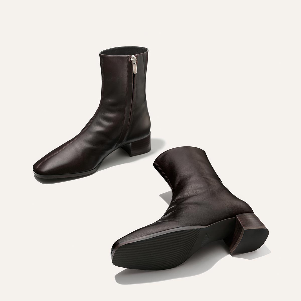 A pair of Margaux’s The Phoebe Boot in Dark Chocolate Calf—crafted from rich leather with a square toe, side zippers, and low block stacked leather heels—displayed on a plain white background for timeless versatility.
