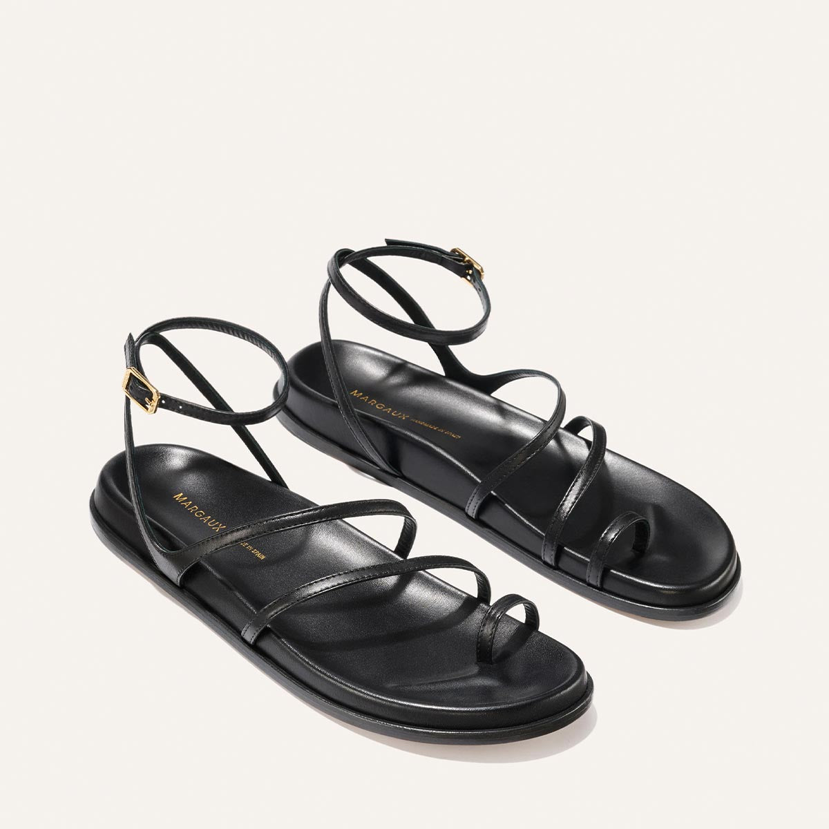 Black strappy sandals on a light gray background