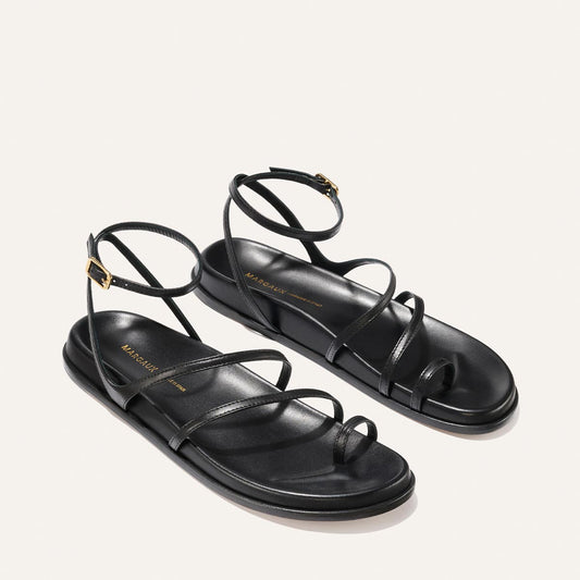Black strappy sandals on a light gray background