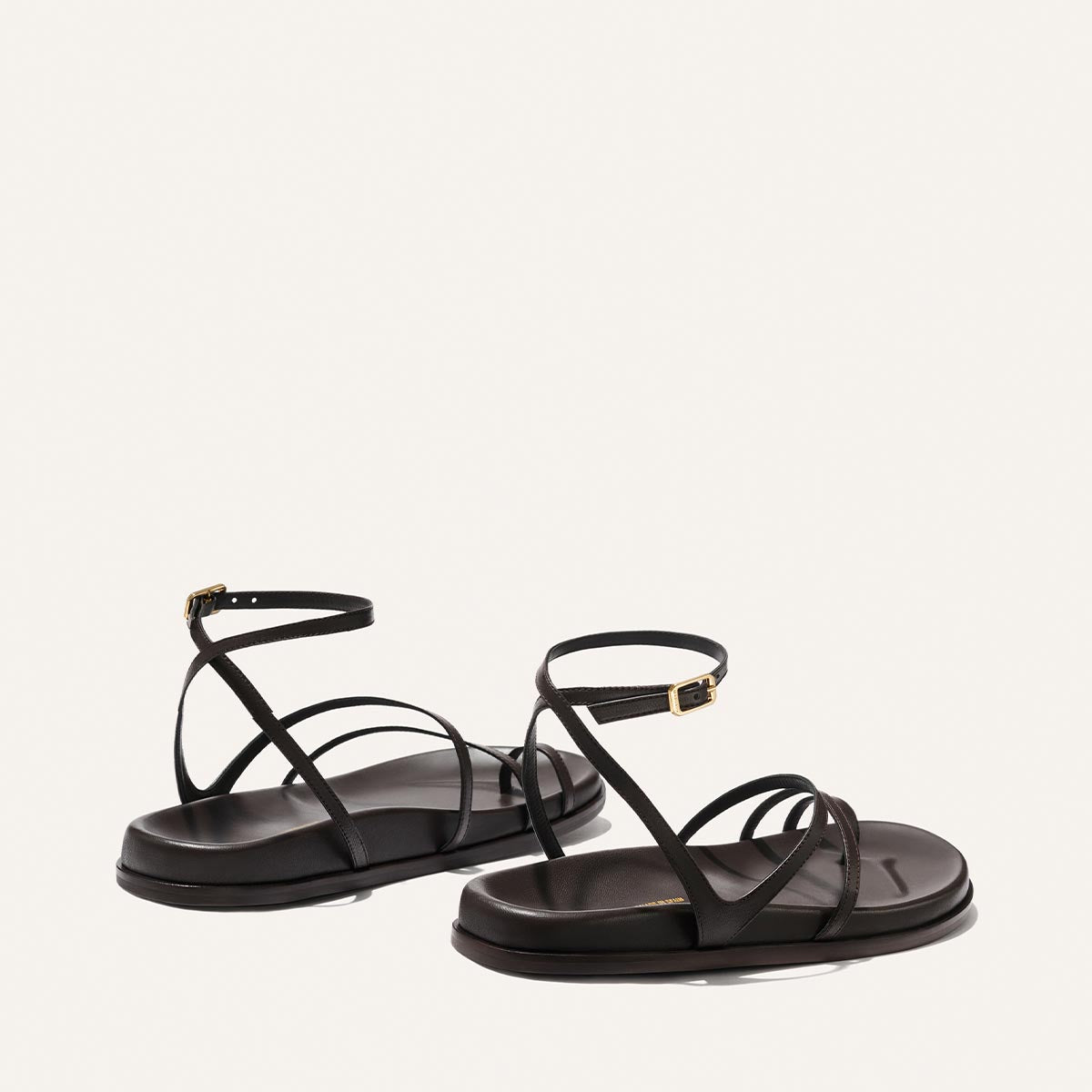 The Vesta Sandal - Espresso Nappa by Margaux, featuring thin crisscross straps and ankle buckles, is shown against a plain white background.