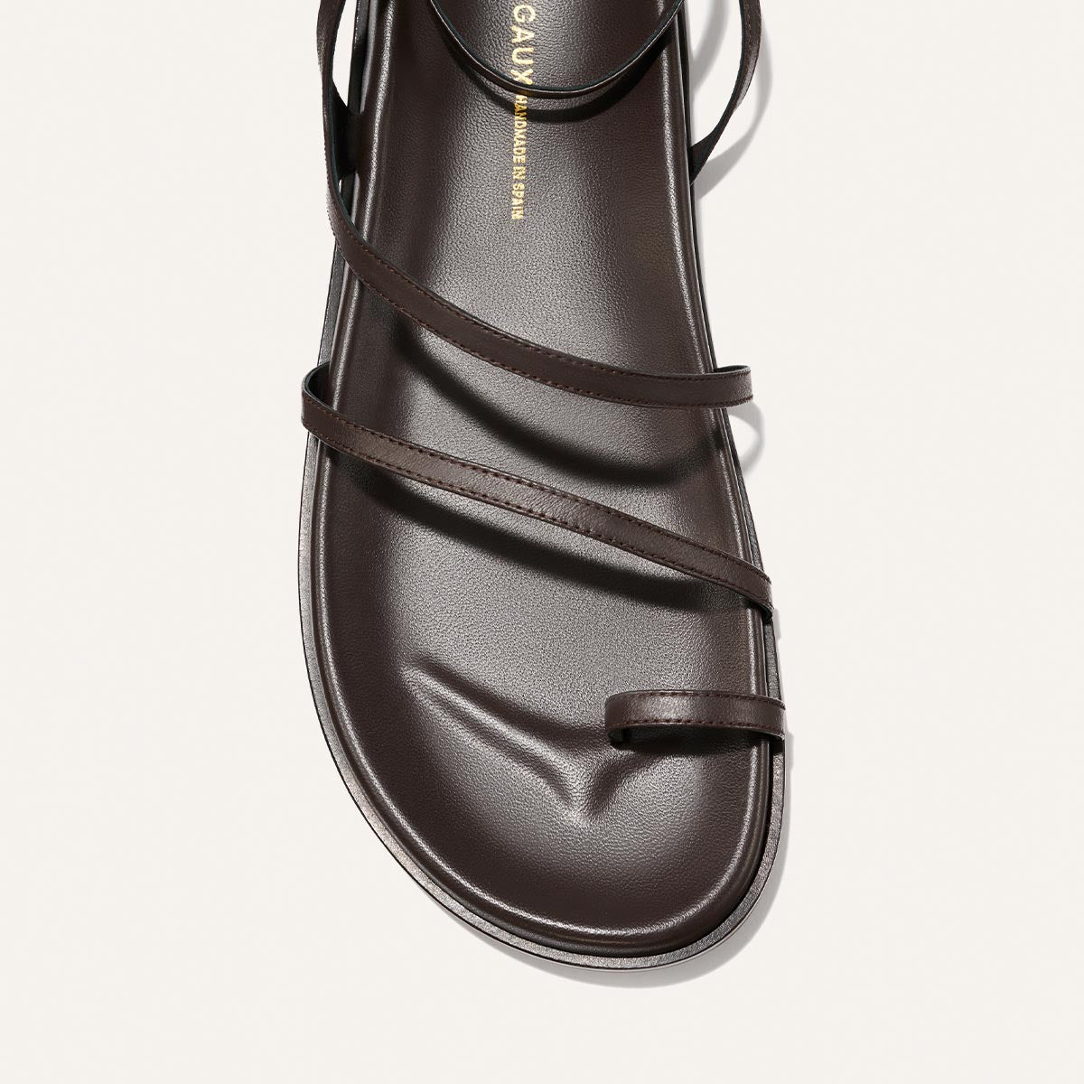 A close-up of The Vesta Sandal in Espresso Nappa by Margaux, featuring thin minimalist straps that cross over the foot and a single toe strap, displayed against a plain white background.