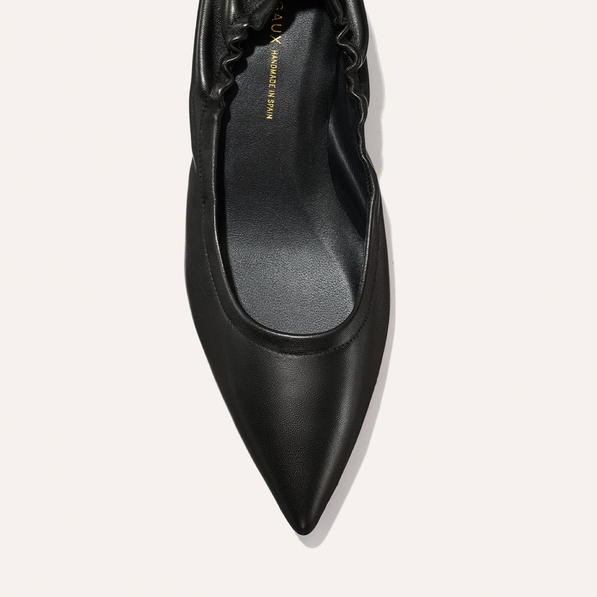 A top view of Margaux’s The Roma 40 - Black Nappa pointed-toe flat, with a ruched elastic back, photographed on a white background.