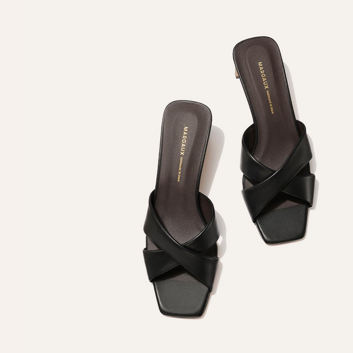 Black high-heeled sandals with criss-cross strap design on a white background
