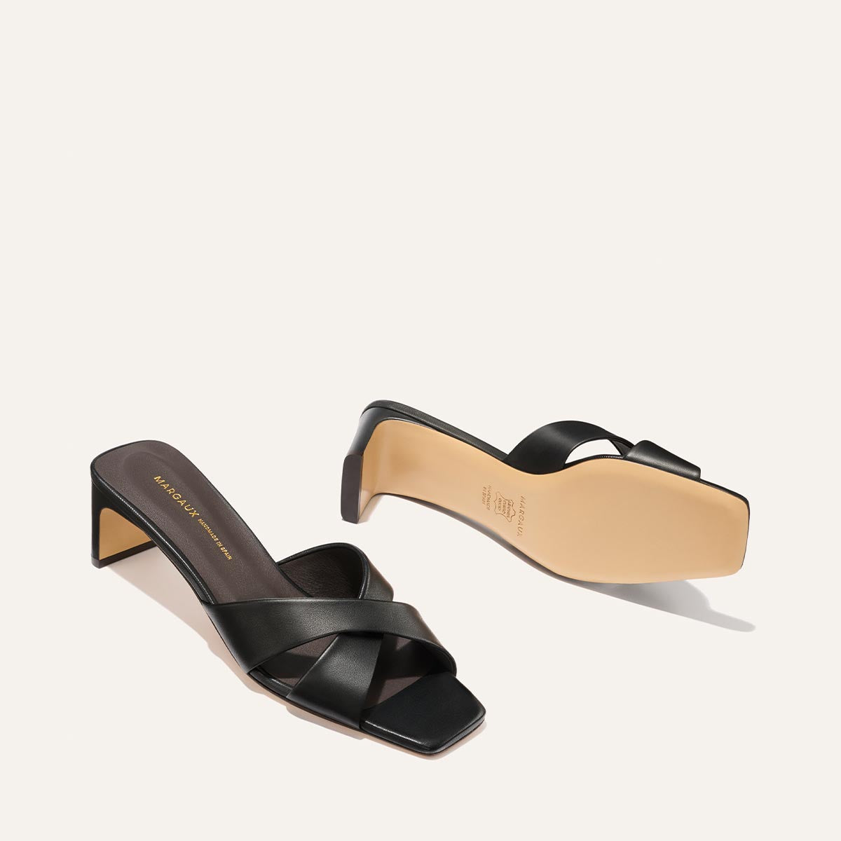 Black high-heeled sandals with criss-cross straps on a white background