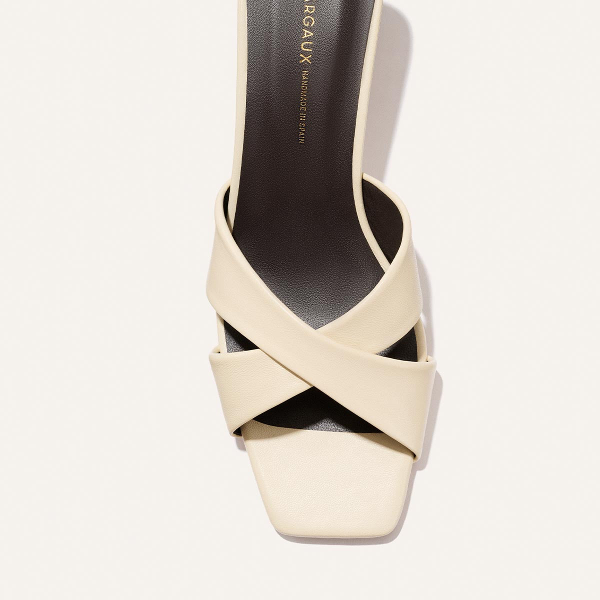 The Margaux Selene 50 - Ivoire Nappa is a cream sandal with wide, crisscrossed straps and a black insole, displayed from above on a plain white background.