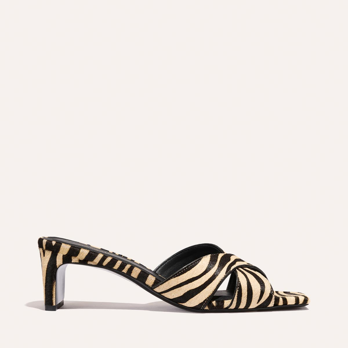 The Selene 50 - Tan Zebra Haircalf by Margaux is a heeled sandal with an open toe and crisscross straps in a black and beige zebra print, shown against a plain light background.