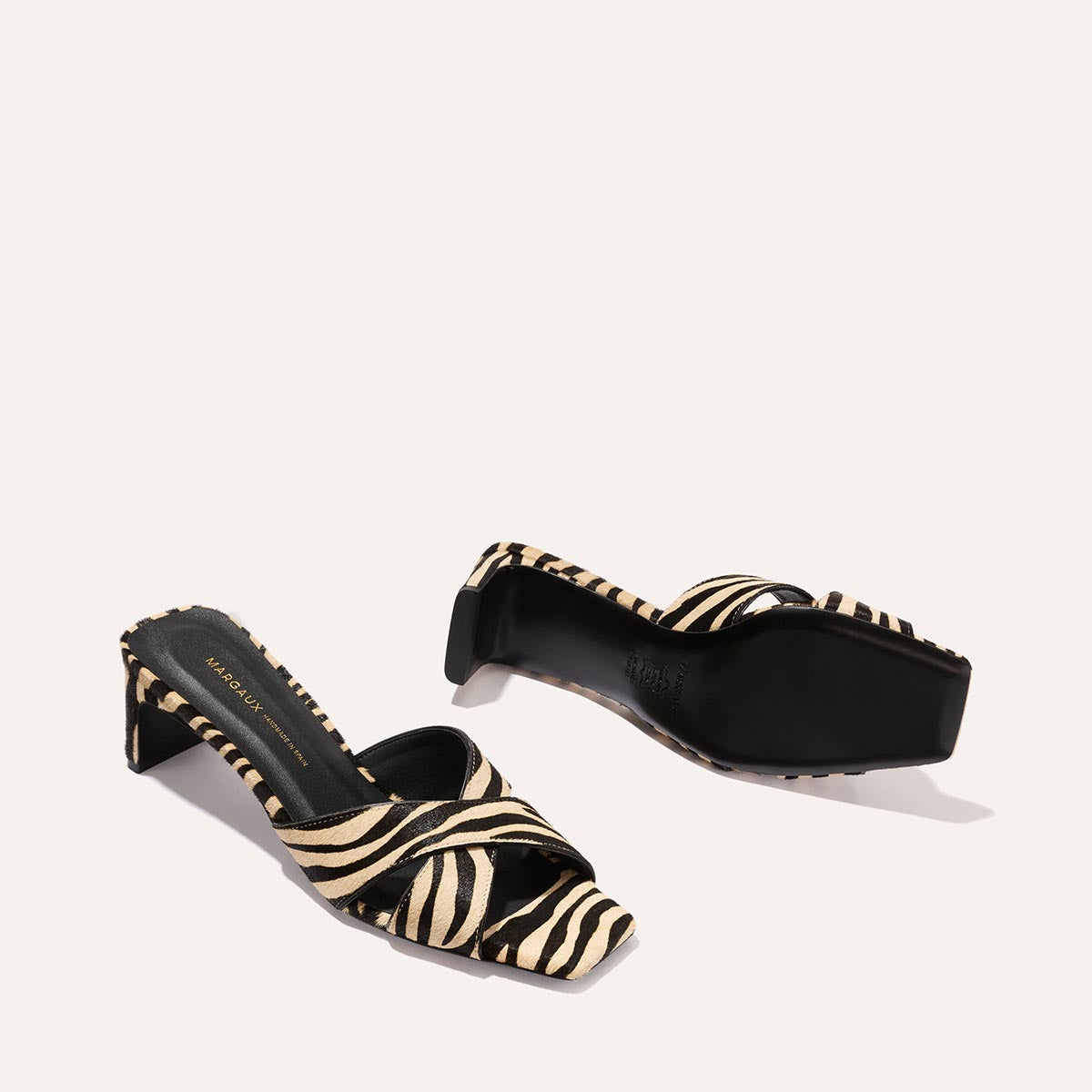 The Margaux Selene 50 - Tan Zebra Haircalf sandals feature black and beige zebra print, square open toes, and black soles, shown against a plain light background.
