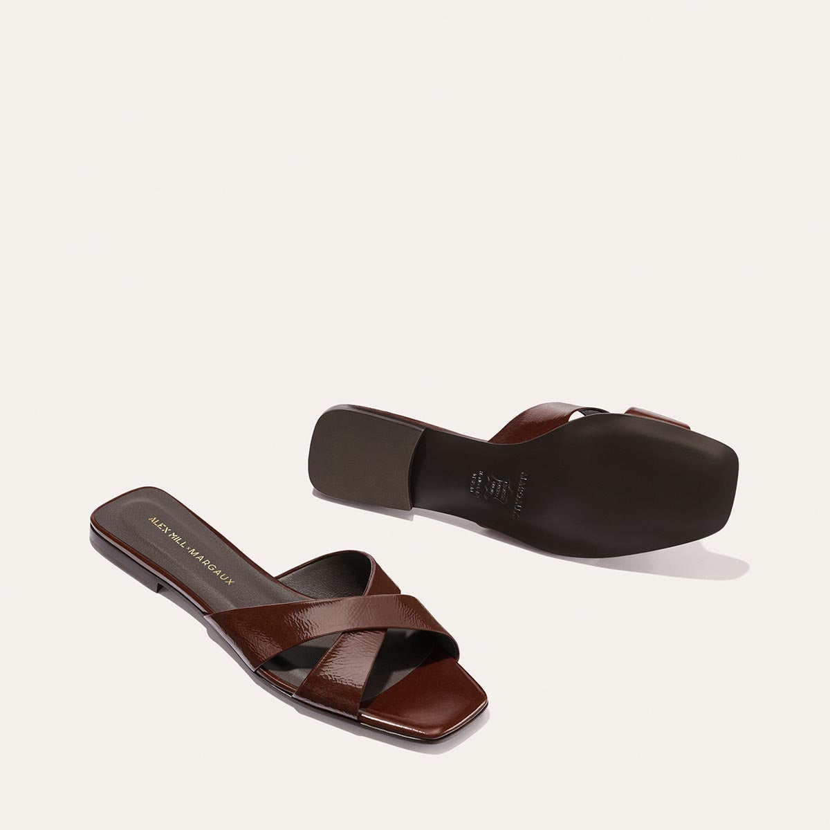 The Alex Mill x Margaux Selene Flat Sandal in Espresso Crinkle Patent features crisscross straps and square toes, shown from multiple angles on a light background—your perfect go-to summer sandal by Margaux.