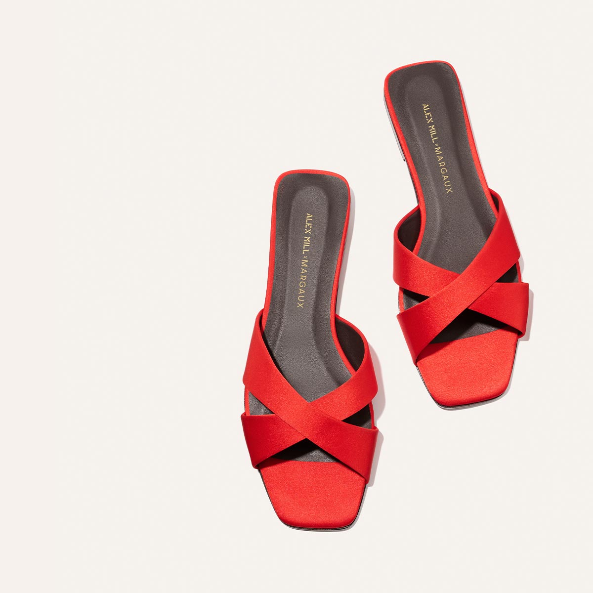 A pair of red Alex Mill x Margaux Selene Flat Sandals in poppy satin with crisscross straps and square toes, featuring Margaux branding on the footbeds—perfect summer sandals, displayed on a white background.