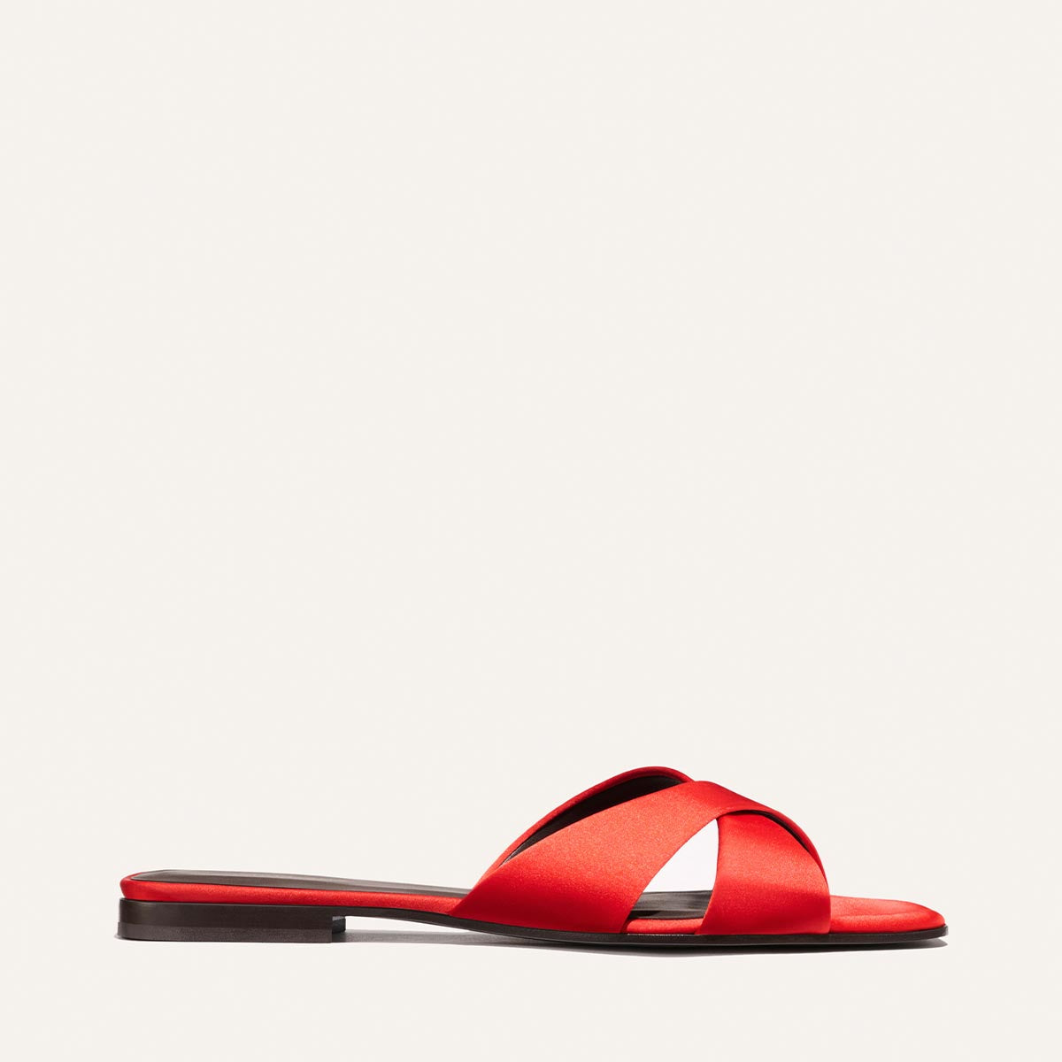 The Alex Mill x Margaux: The Selene Flat Sandal in Poppy Satin features wide crisscross straps, an open toe, and a flat slip-on design in red—shown side profile on white—perfect for summer by Margaux.