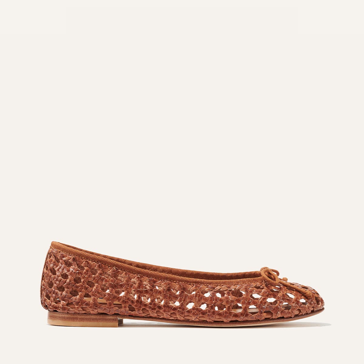 The Demi - Saddle Woven Leather by margaux-development is a brown woven leather ballet flat with a closed toe, bow detail, and flat sole, handmade in Spain and shown on a plain off-white background.
